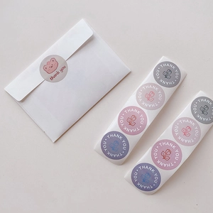 Detailed view of white envelope with bear stickers and colorful floral thank you labels