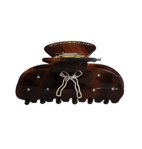 Detail of tortoise shell claw clip with rhinestones and a white bow pattern