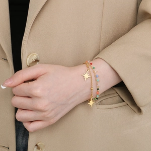 Close-up of double-layer gold bracelet with stars and colorful beads on wrist