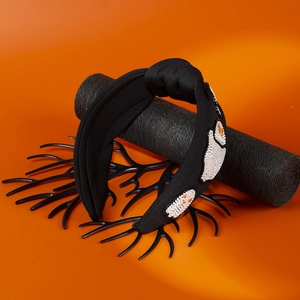 Detailed embroidery of beaded ghost patterns on a wide black knotted Halloween headband