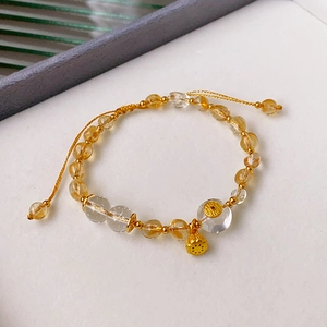 Detail of beaded bracelet featuring citrine, quartz, and a gold lotus pod charm