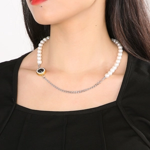 Close-up of asymmetric necklace with white pearls, silver chain and black round pendant