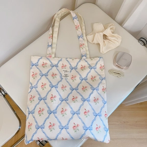 Close-up of floral tote bag with blue ribbon patterns and delicate pink rose prints