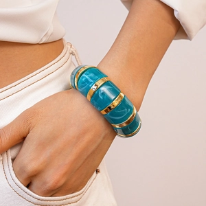 Detail of blue marble resin and gold metal link bracelet on a woman's wrist
