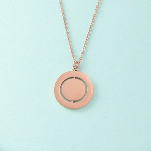 Detail of rose gold geometric necklace with rotating double round pendant on blue surface