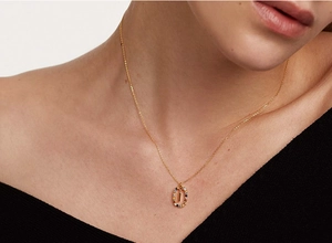 Model wearing gold necklace with oval colorful gemstone pendant for elegant look