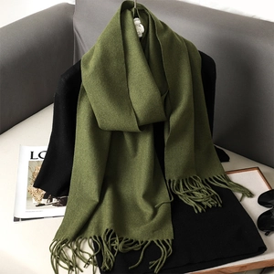 Detail of soft green autumn scarf with fringe styling on a black outfit background