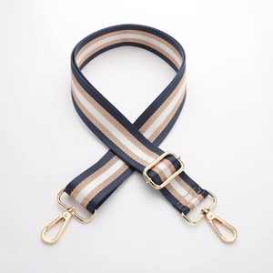 Close-up of adjustable striped canvas bag strap with golden metal swivel hooks