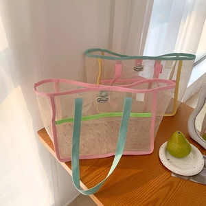 Close-up of mesh tote bags with contrast webbing handles on a bright wooden table