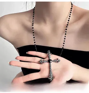 Macro detail of gothic cross pendant with black gemstone and ornate floral engravings