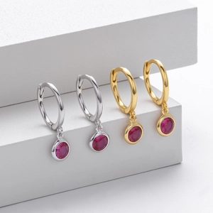 Detail of S925 sterling silver hoop earrings with ruby red gemstone charms in gold and silver