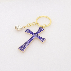 Detail of golden keychain with blue rhinestone cross and clear crystal pendant