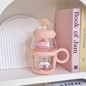 Detail of pink glass straw cup with silicone sleeve featuring a cute cartoon dog pattern
