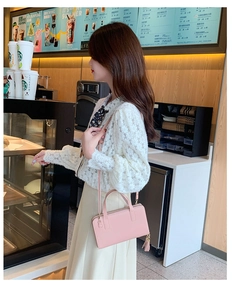 Detail of pink double-layer crossbody bag with tassel charm and slim shoulder strap