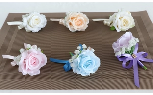 Detail showing six colors of artificial rose corsages with ribbons and greenery