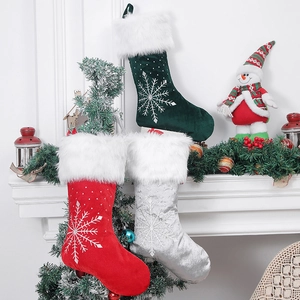 Three velvet Christmas stockings with snowflake embroidery on a festive fireplace mantel
