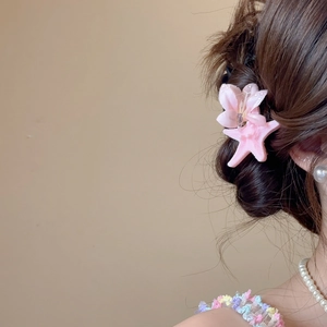 Close-up of pink fabric flower and starfish hair clips with rhinestones on dark brown hair