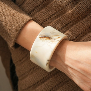 Close-up of retro marble pattern resin bangle on a wrist with brown knit sweater