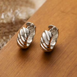 Chic silver twisted rope croissant hoop earrings on a rustic wood background
