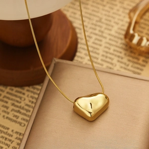 Detailed view of a golden heart pendant necklace on jewelry box with mirror finish