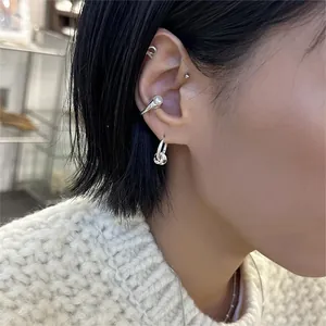 Detail of silver S925 earrings with pearl ear cuff and knot drop design worn by model