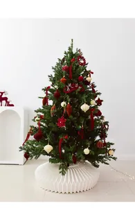 Detail of velvet Christmas balls and stars hanging on a green tree with a modern white base