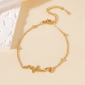 Detail of gold titanium steel bracelet featuring heartbeat line and small heart charm