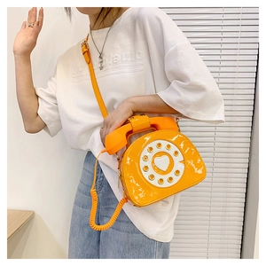 Detail shot of bright orange patent leather crossbody bag with creative vintage telephone design