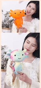 Close-up of orange and rainbow plush axolotl toys being held by a hand in a soft setting