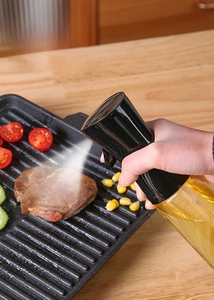 Action shot of the oil sprayer producing a fine mist over a steak in a frying pan