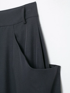Detail of high-waist dark grey trousers showing side pockets and twill fabric texture