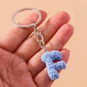 Detail of floral letter F keychain featuring light blue roses and a silver metal ring