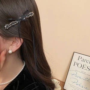 Close-up of elegant black bow hair clip with gray crystals and pearls on model