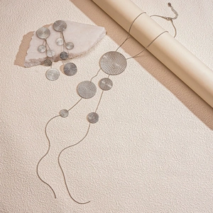 Detail of silver long tassel necklace and earrings with textured geometric round plates