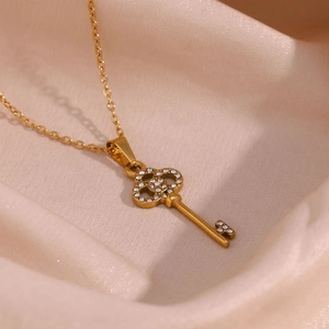 Close-up of golden clover key pendant with pavé set zircons on silk background