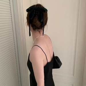 Detail of a large black fabric bow hair claw clip styled on a woman's elegant hairstyle