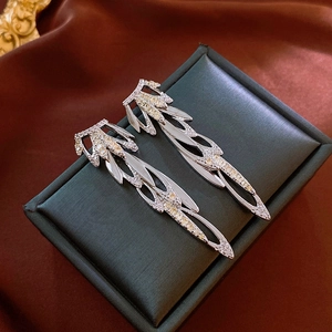 Elegant wing-shaped leaf drop earrings with sparkling zircon crystals on dark satin