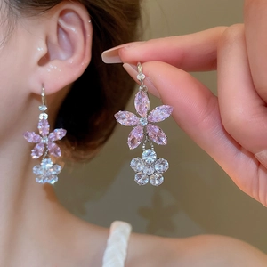 Gros plan d'une boucle d'oreille fleur avec zircon rose sur l'oreille du mannequin