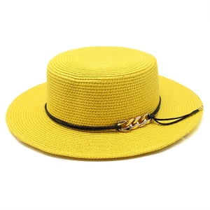 Détail d'un chapeau de paille jaune à sommet plat avec chaîne dorée et cordon noir