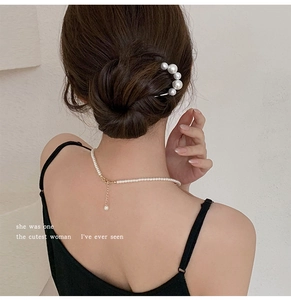Detail of elegant U-shaped pearl hair pin and matching necklace on a model