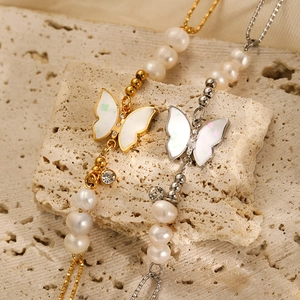 Close-up of golden and silver butterfly charms with white pearls on elegant stone