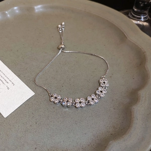 Close-up of floral zircon clusters and adjustable bolo clasp on a silver-tone bracelet