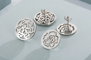 Detail of silver hollow earrings featuring rose and floral patterns on blue background