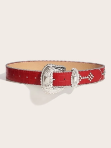 Close-up of red crocodile-embossed leather belt with vintage silver buckle and studs