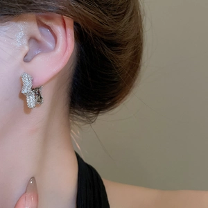 Close-up of sparkling zircon irregular star hoop earrings worn on a model's ear