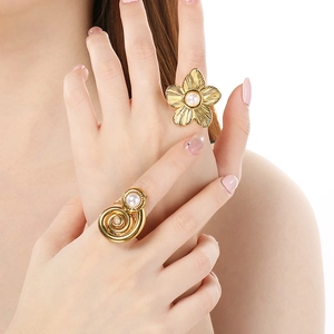 Detail von goldenen Blumen- und Spiralperlenringen an der Hand für einen schicken Look