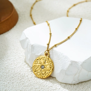 Vue détaillée du pendentif étoile en or 18K avec zircon sur fond de pierre blanche