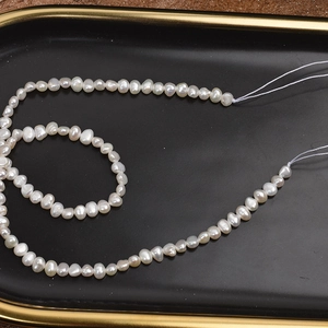 Natural 4-5mm baroque freshwater pearl strand in milk white on a black tray