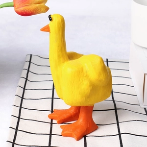 Close-up of a creative yellow resin duck figurine on a black and white checkered mat