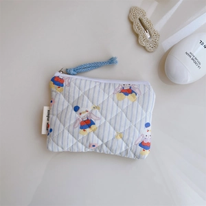 Détail de la pochette matelassée en coton avec motifs d'oies et fermeture éclair bleue tissée